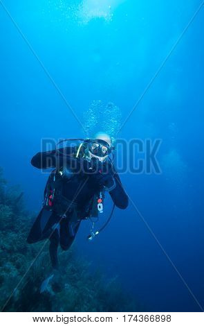 Happy young scuba diver swimming near coral reef Cuba