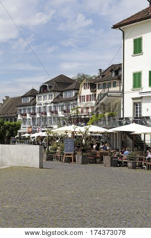 RAPPERSWIL SWITZERLAND - MAY 10 2016: Buildings of the city. There are several people in the outdoor restaurant who can be seen in a distance