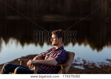 Man Relaxing by a Lake in Forest. Rest of Hipster Freelancer