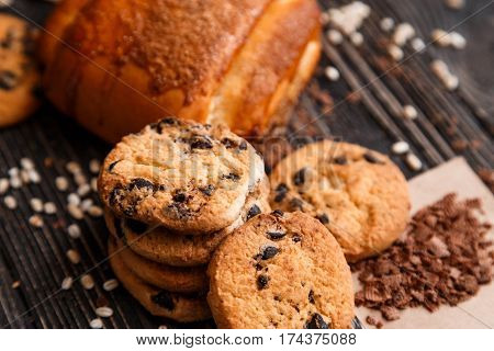 Stacked chocolate chip cookies and cinnamon bun with chocolate on brown napkin