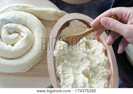 Female Hand Picking Up Molten Cheese From Wooden Bowl