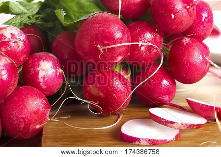 Fresh, juicy, appetizing radish lying on a wooden table in front of treatment in lettuce