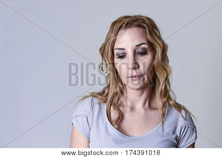 blond attractive woman on her thirties sad and depressed looking desperate in sorrow and grief facial expression in female depression emotion concept isolated on grey background