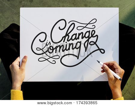 Hand Holding Pen Paper Writing Change is Coming Board
