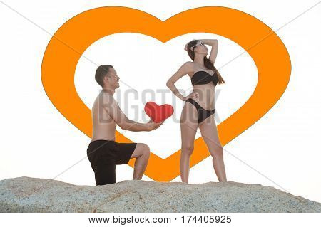 Lovely young adult couple standing on the rocks above tropical sea in isolated.
