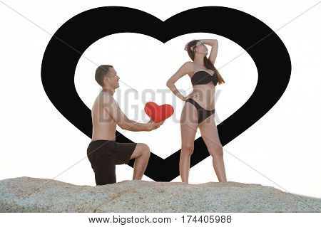 Lovely young adult couple standing on the rocks above tropical sea in isolated.