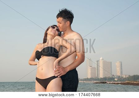 Lovely young adult couple standing on the beach.