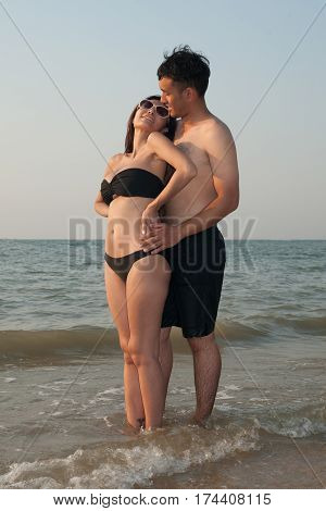 Lovely young adult couple standing on the beach.