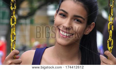 Happy and Smiling Teen Girl Swinging On Swingset