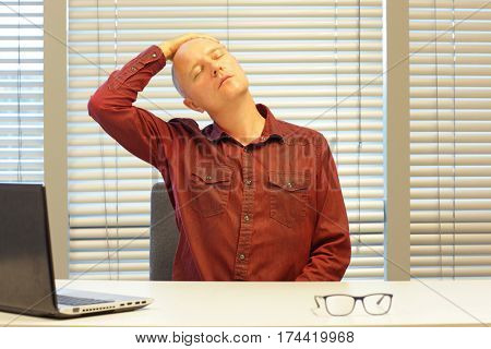 middle age balding man relaxing neck - short break for exercise on chair in office