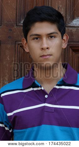 Serious Teen Boy Standing Next to Wooden Door