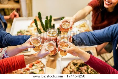 Group of happy friends cheering at home with beer - Young people having fun together eating italian pizza take away - Dinnerparty and friendship concept - Focus on left woman hand