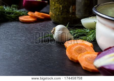 garlic dill cut carrot cut red onion boiled egg near iron tureen and bowl of sorrel on dark wooden table. Small depth of focus