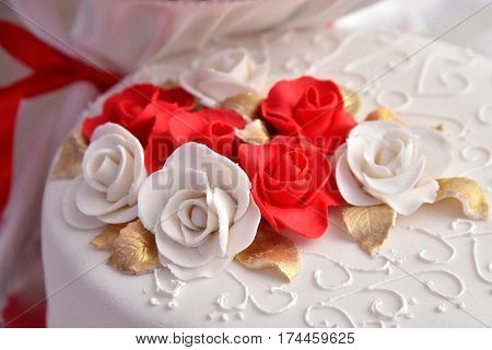 Sweet cakes in the form of red roses decorate the wedding cake with more decorative twigs of white cream. Photographed at a wedding in Novi Sad, Serbia.