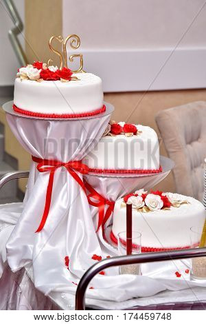 Sweet cakes in the form of red roses decorate the wedding cake with more decorative twigs of white cream. Photographed at a wedding in Novi Sad, Serbia.