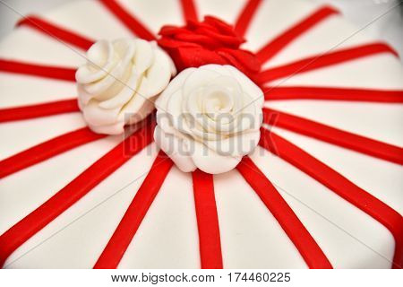 Sweet cakes in the form of red roses decorate the wedding cake with more decorative twigs of white cream. Photographed at a wedding in Novi Sad, Serbia.