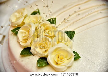 Cute delicious wedding cake decorated with cakes in the shape of red and white roses on the sides decorated with various beads and lines