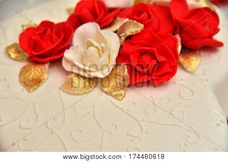 Sweet cakes in the form of red roses decorate the wedding cake with more decorative twigs of white cream. Photographed at a wedding in Novi Sad, Serbia.
