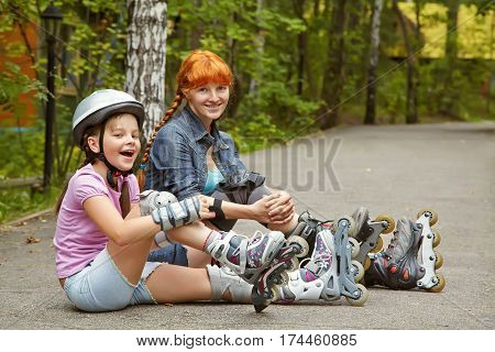 sports mother and daughter in a helmet. family on the skates. two people rollerblade. rollerskating outdoor
