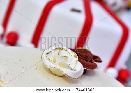 Cute delicious wedding cake decorated with cakes in the shape of red and white roses on the sides decorated with various beads and lines