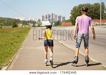 Dad with little daughter on the skates. two people rollerblade. sports family rollerskating outdoor