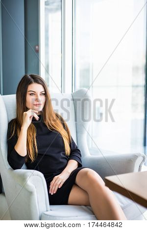 Attractive young woman sitting on a chair in a cafe