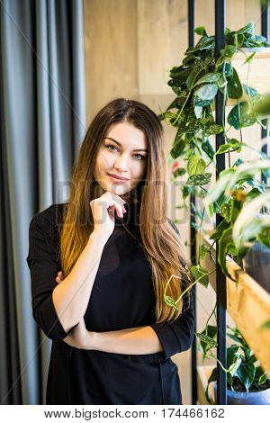 Friendly businesswoman standing with folded arms in a bright neat office looking at the camera