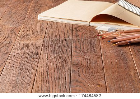 Noteboks and colorful pencils on the wooden table, eraser. Brown background. Creative concept and idea. Art and design. Writing, drawing, painting.