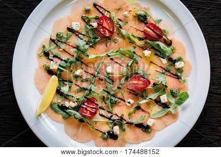 Salmon carpaccio with arugula leaves and sticky balsamic vinegar