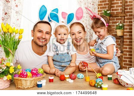 Happy easter! family mother father and children having fun paint and decorate eggs for holiday