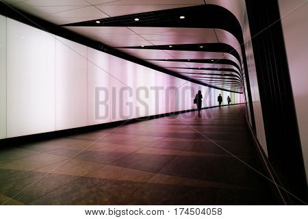 LONDON, UK - MAY 17, 2016: People walking through futuristic looking pedestrian tunnel featuring an LED integrated light wall in Granary Square exit from Kings Cross Underground station.