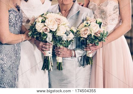 Women generation family and bride holding flowers bunches on wedding day.