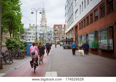 AMSTERDAM. NETHERLANDS - JUNE 2016 Bicycle path in the city centre of Amsterdam with a string of cyclists on bikes. Street with a view of the South Church Zuiderkerk. Netherlands. Horizontal Image