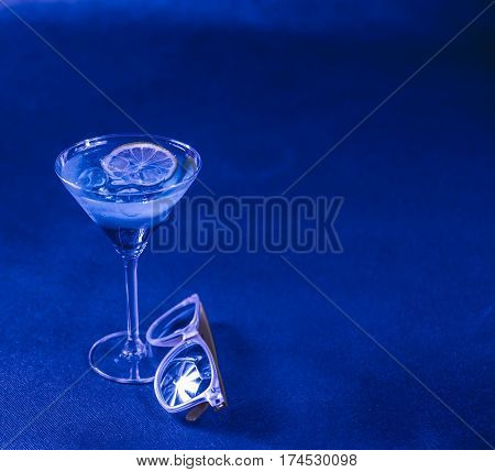 blue background mixed drink lemon martini glass yellow sunglasses party set