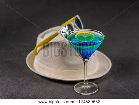 colored drink a combination of blue and green lemon martini glass yellow sunglasses on white hat party set