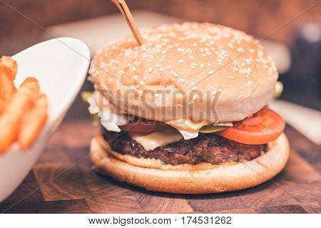 Burger with fresh tomato cheese meat and french fries. Selective focus.