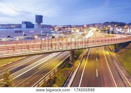 BARAKALDO SPAIN - MARCH 5 2017: Car light trails in the highway near the city of Barakaldo and the Bilbao Exhibition Center (BEC). Long exposure shot at sunset.