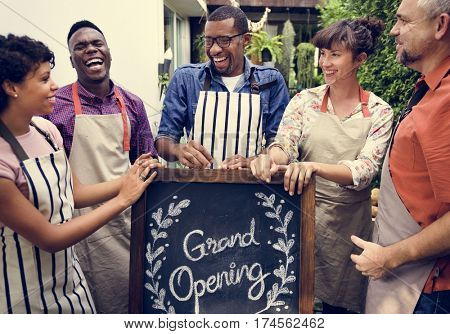 Group of friends with grand opening board together