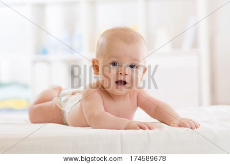 Portrait of a three months old baby boy on the bed in nursery room