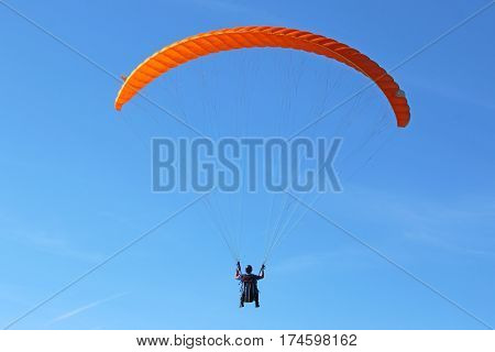 Paraglider flying his wing in a blue sky