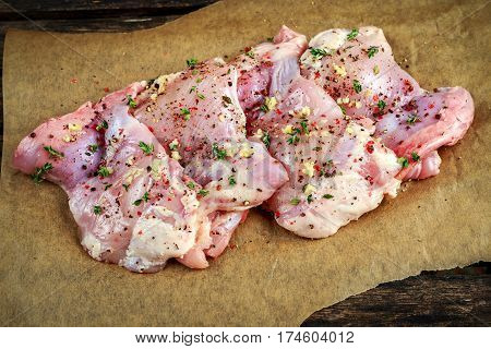 Ready to cook free range raw boneless skinless chicken thighs on paper seasoned with sea salt, garlic and pepper.