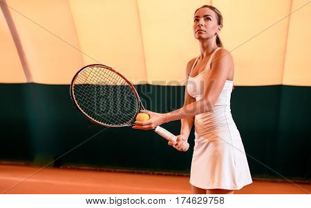 Sportswoman at the tennis court with racquet. Indoor tennis court