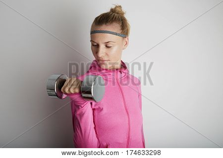 Portrait of fitness young woman wearing pink sports wear. Fresh healthy stylish sport girl posing close to white wall.