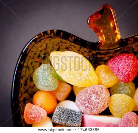 colored candies inside an apple-shaped glass bowl