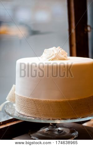 white cake decorated with two roses on top in front of a window