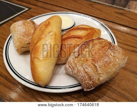 Assortment of different types of French bread as side dish serve with salted butter on table focus-on-foreground bread with blur bread and table background