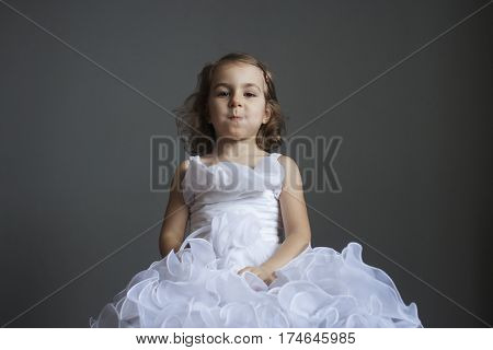 Little girl in a smart white dress. Human emotions. Joke tomfoolery