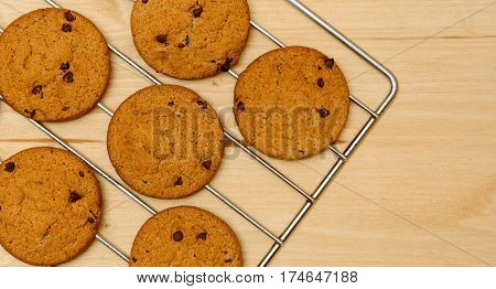 Freshly baked Chocolate chip cookies on cooling rack over wood background.