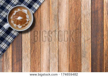 Hot cappuccino on fabric on wood table top view