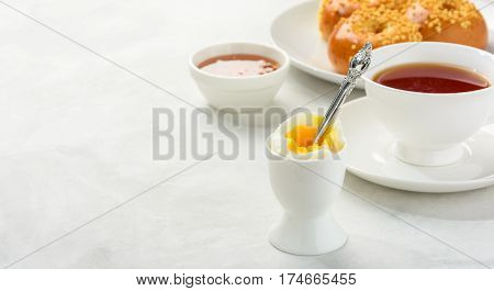 Delicious and healthy breakfast of boiled egg and brioche buns with black tea on a light background. Copy space soft focus .